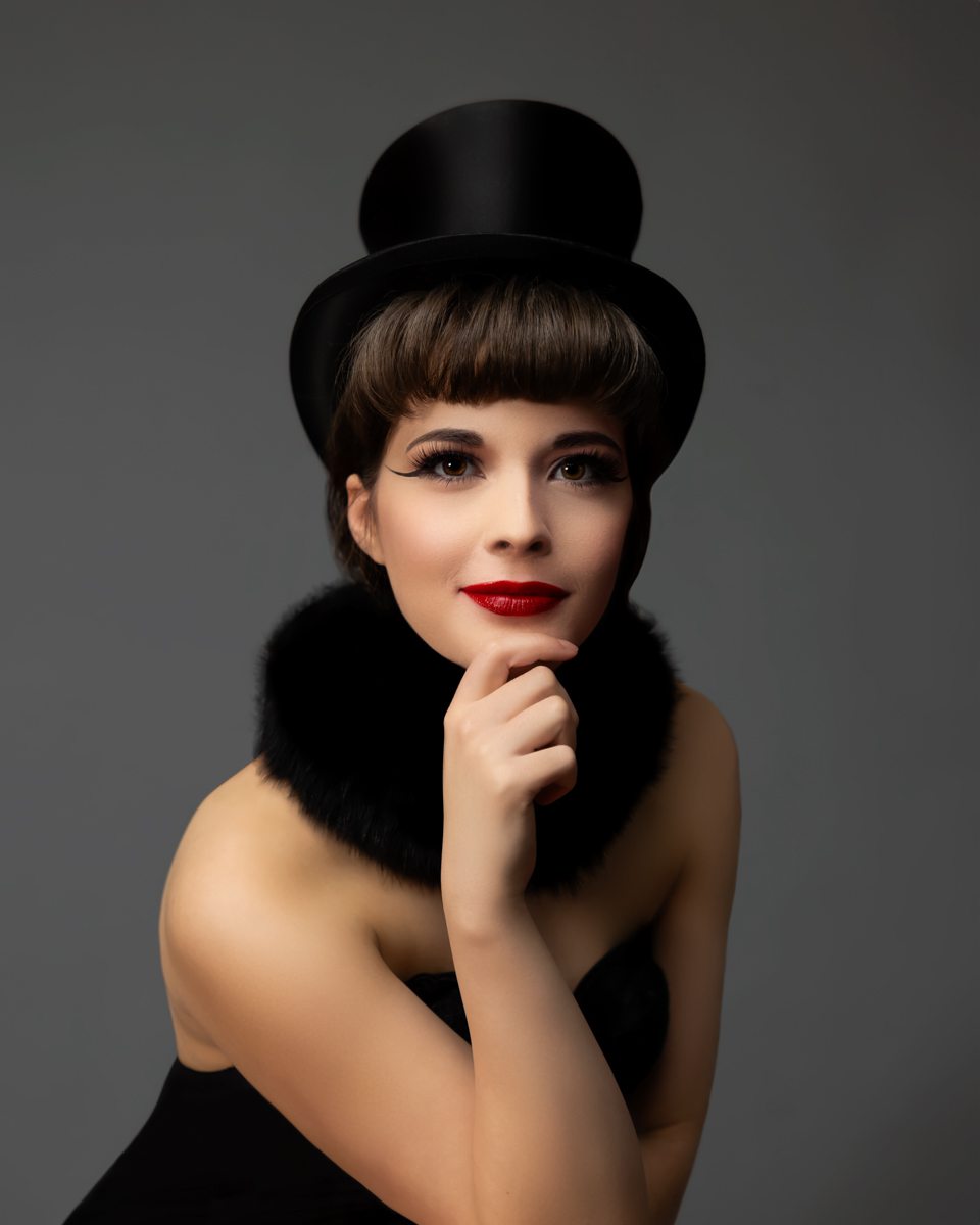 A woman in a bustier dons a top hat & fur