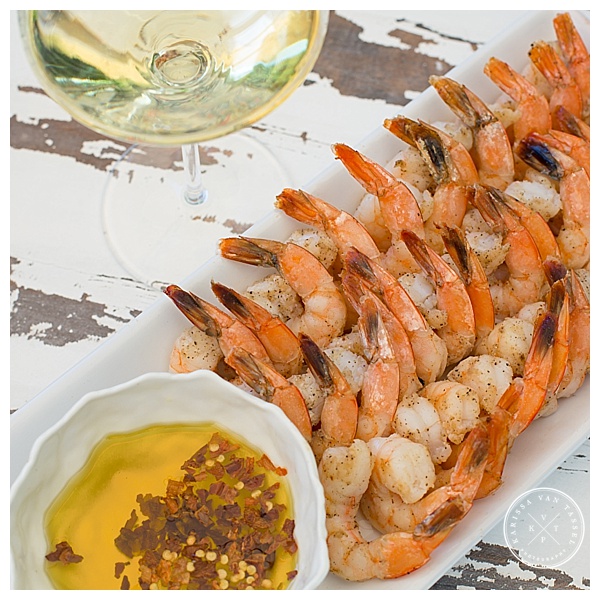 A shrimp appetizer is set beside a glass of chilled white wine.