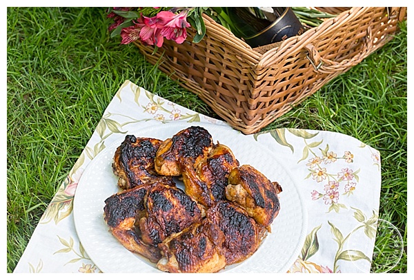 Food photography featuring a picnic basket complete with champagne and grilled chicken