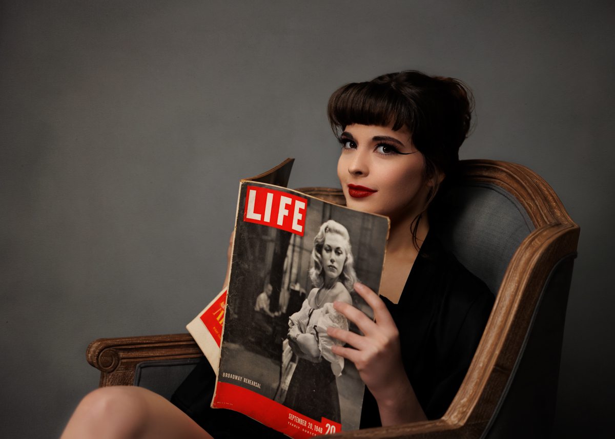 A woman sits in a chair with an old Life magazine